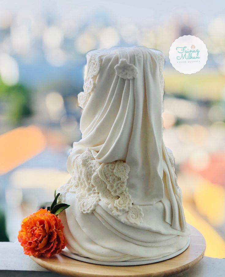 a white cake with an orange flower sitting on top of it