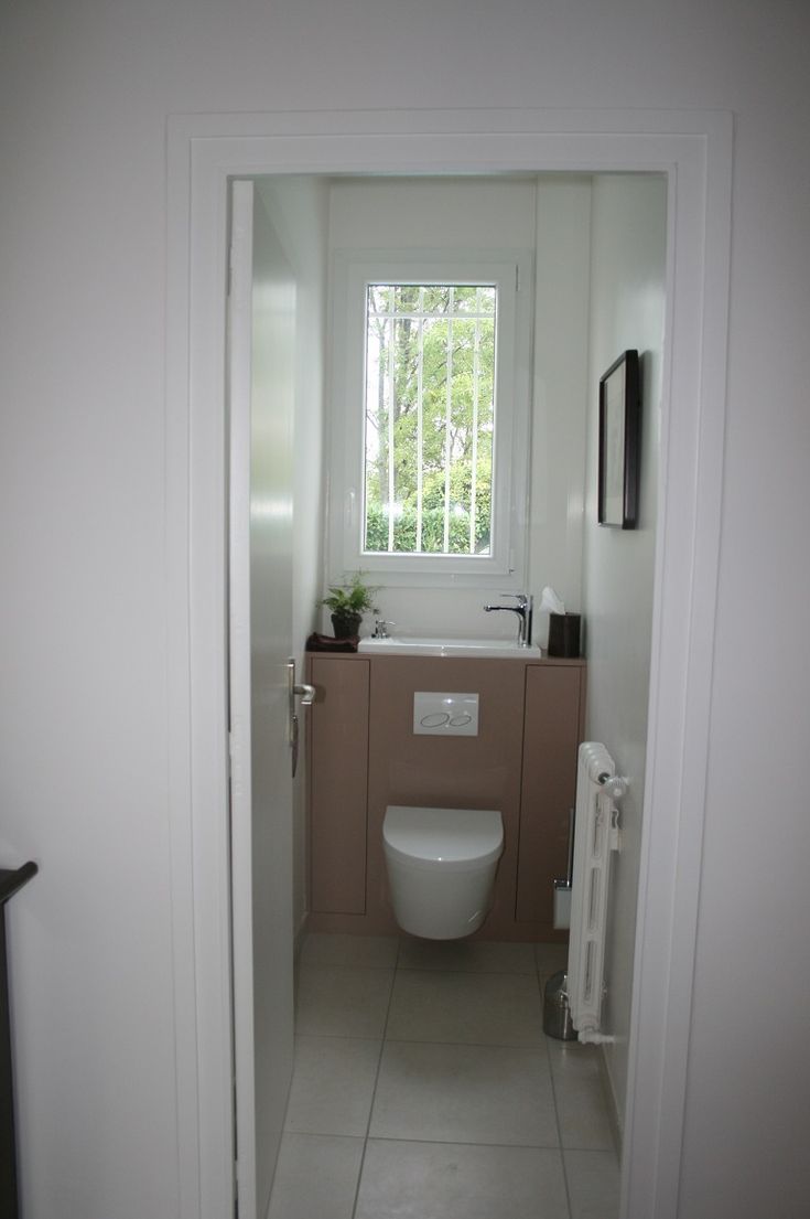 a white toilet sitting in a bathroom next to a window