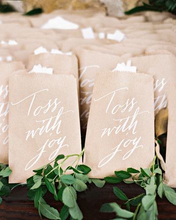 small brown bags with white calligraphy on them are lined up next to greenery