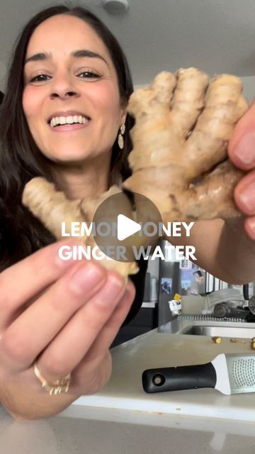 a woman holding up some food in front of her face with the caption lemon honey ginger water