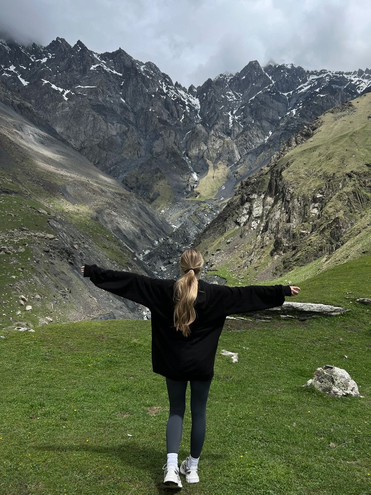 a woman standing on top of a lush green hillside