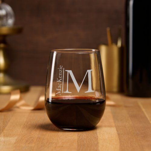 a wine glass with the letter m on it sitting on a table next to some bottles