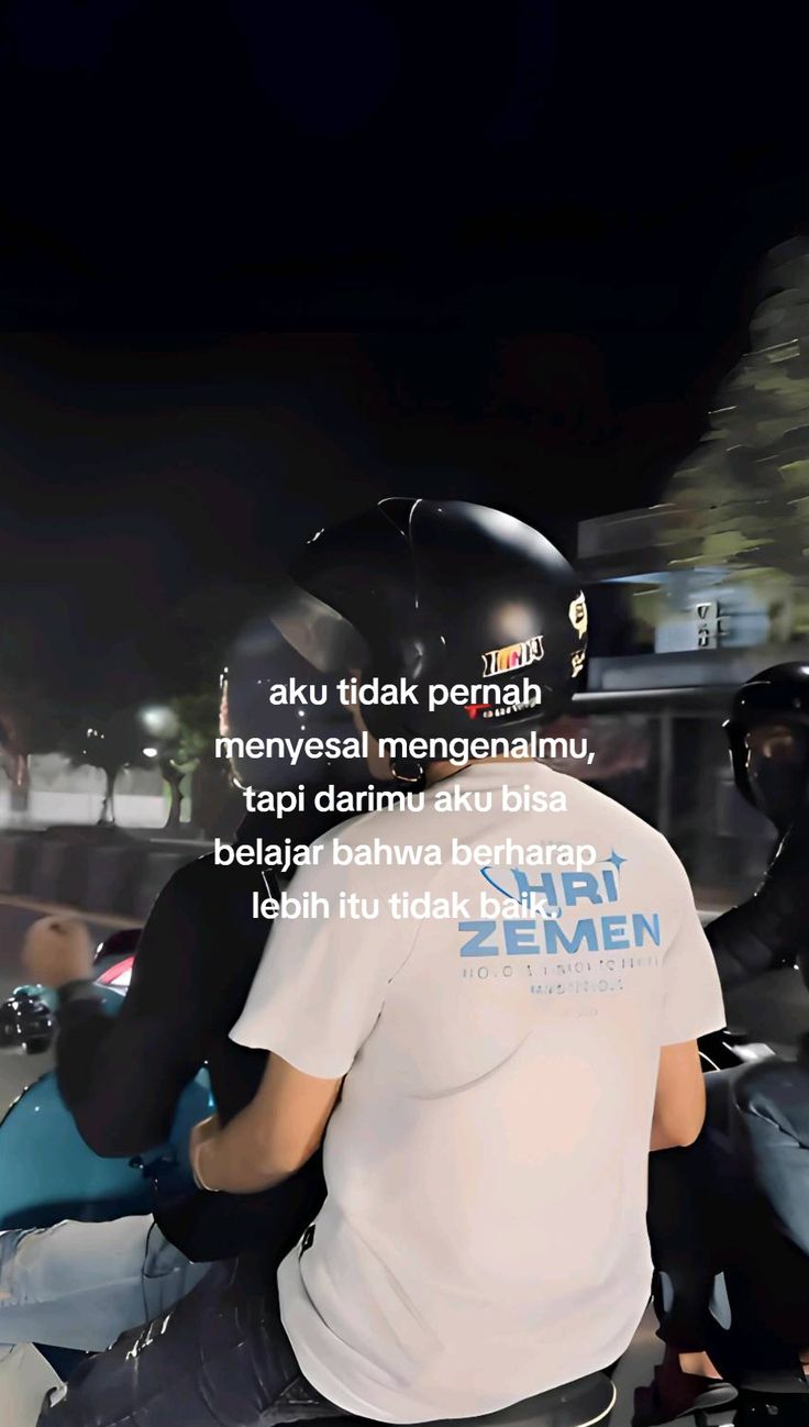 a man riding on the back of a motorcycle down a street at night with words written below him