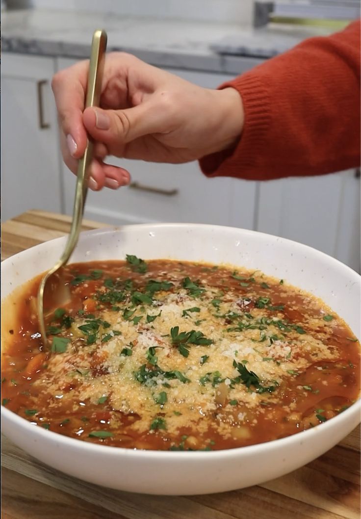 a person holding a spoon in a bowl of soup