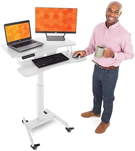 a man standing next to a computer desk with a laptop on it