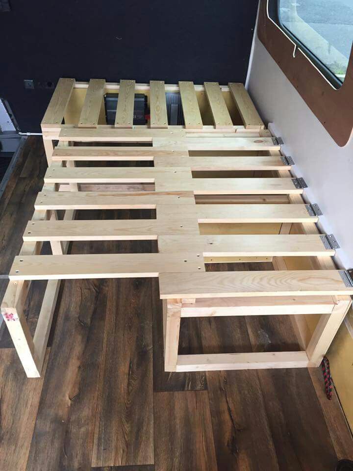 a bed frame made out of wood sitting on top of a hard wood floor next to a window