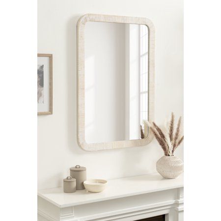 a white fireplace with a mirror on the mantle and a potted plant next to it