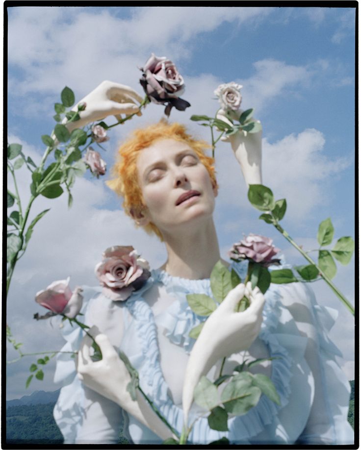 a woman with red hair and flowers on her head is looking up at the sky