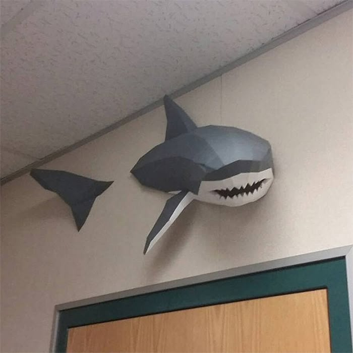 two paper shark masks hanging from the ceiling above a door in front of a wooden door