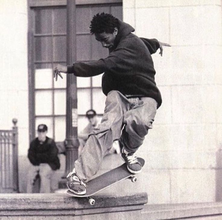 a man riding a skateboard up the side of a cement wall next to a building