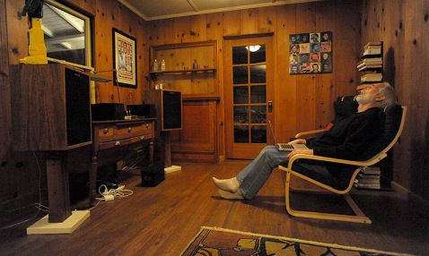 an older man sitting in a chair with his feet up on the floor while watching tv