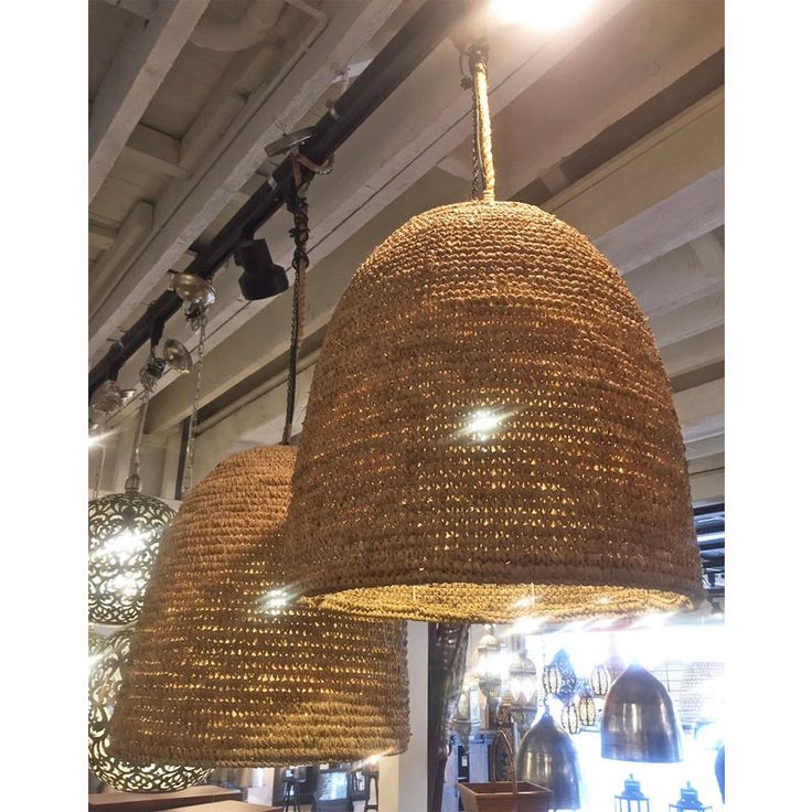 two woven lamps hanging from the ceiling in a room with other items on display behind them