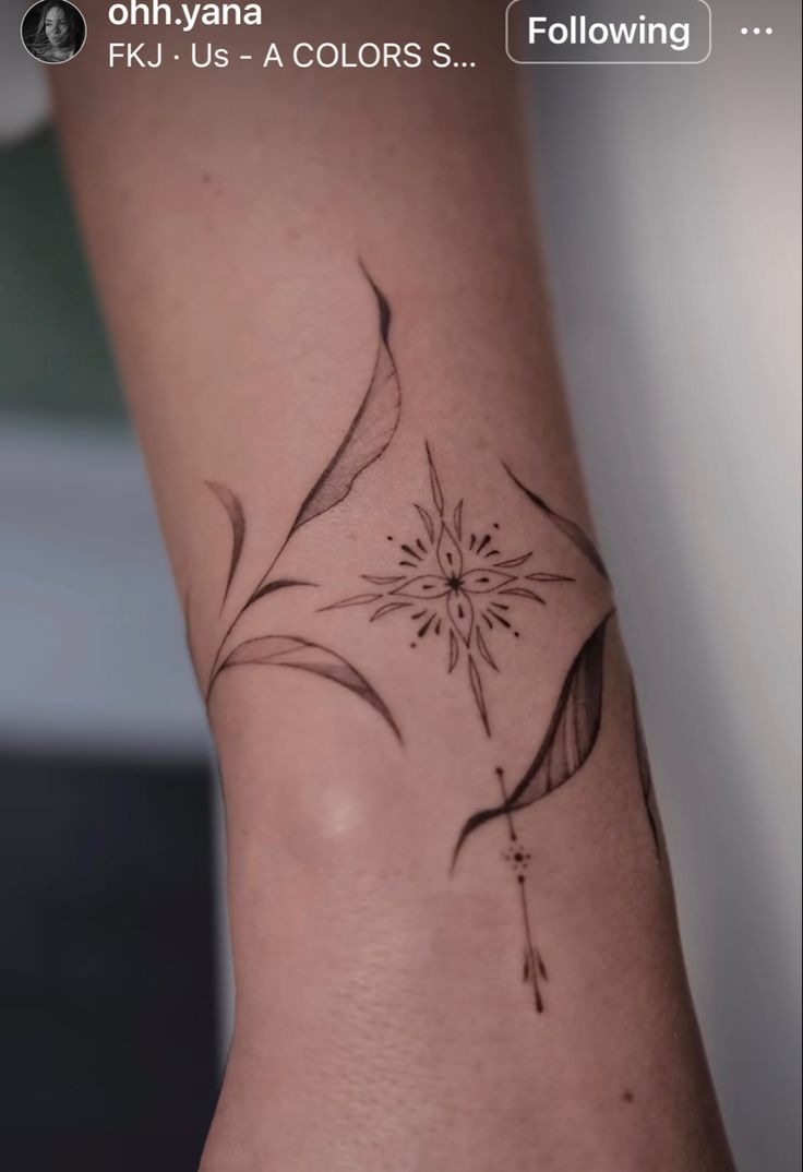 a flower tattoo on the wrist is shown in black and grey colors, with an arrow at the center