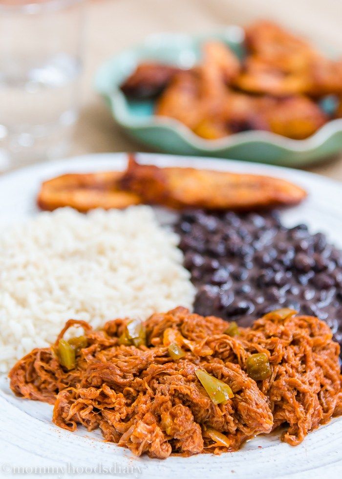 a white plate topped with rice and beans next to other foods on a wooden table