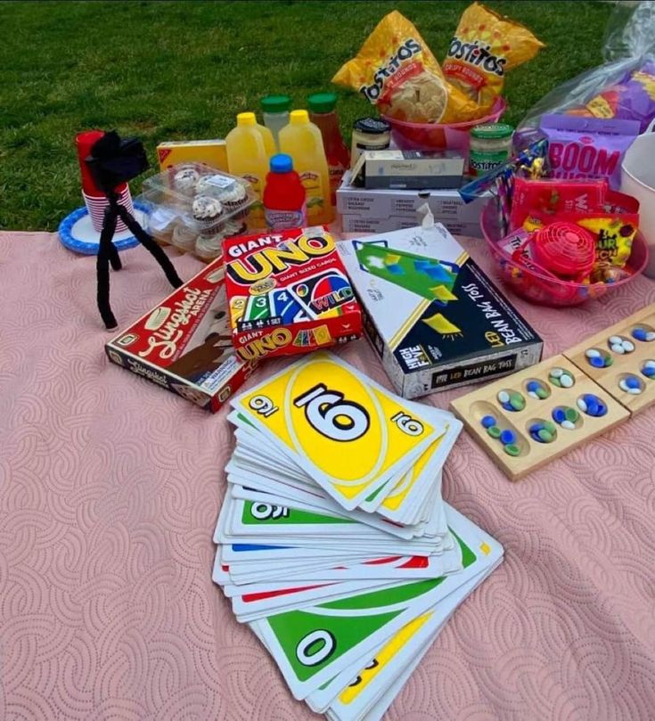 the picnic table is full of snacks and other items to play with on the grass