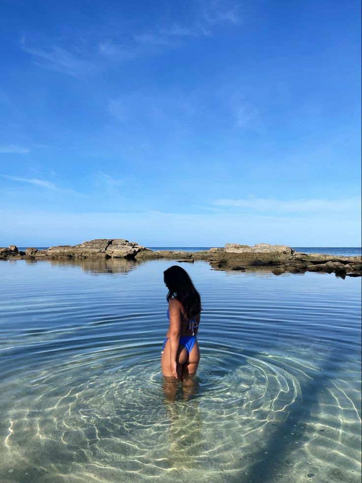 a woman standing in the water with her back turned to the camera