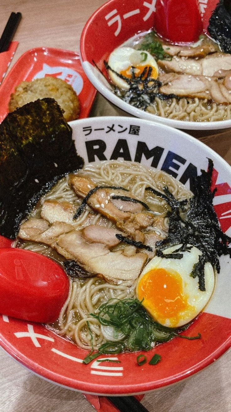 two bowls filled with ramen and vegetables on top of a table