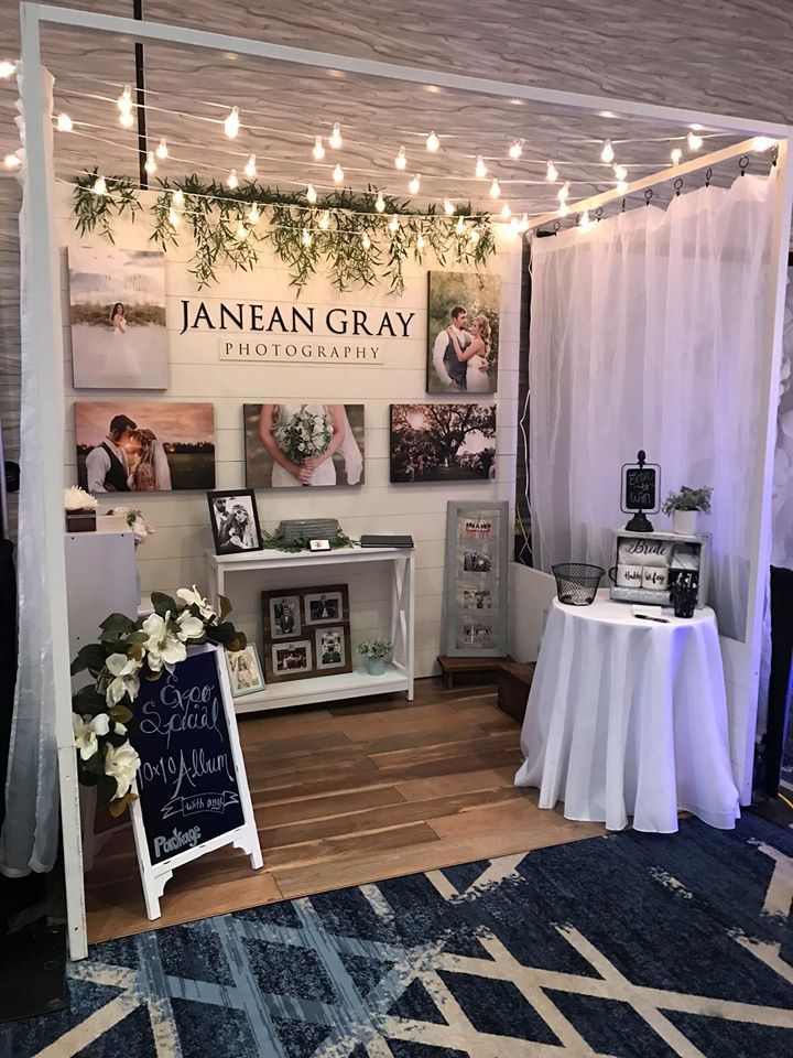 a booth at an event with pictures on the wall and lights hanging from the ceiling