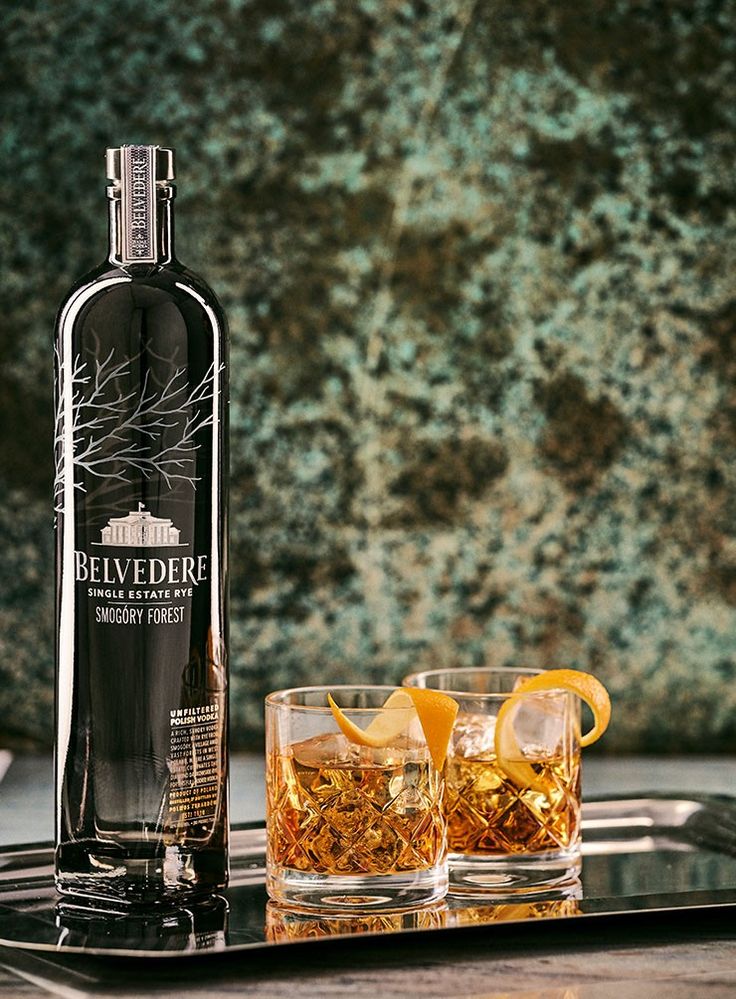 a bottle of belvedere gin and two glasses on a metal tray with rocks