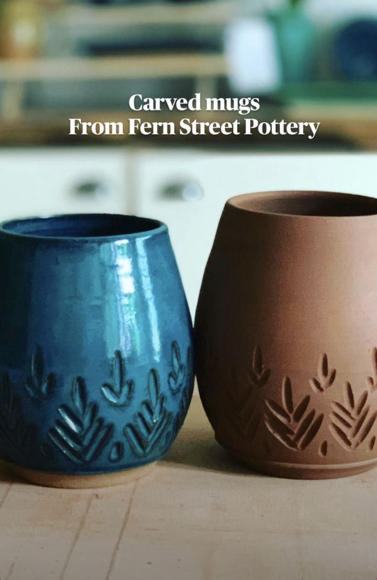 three ceramic mugs sitting on top of a wooden table in front of a kitchen counter