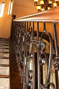 an iron stair railing with wood handrails and chandelier on the top