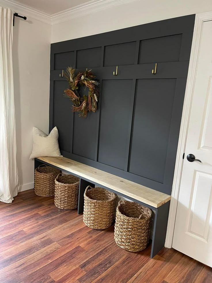 a bench with baskets on it in front of a white door and wooden flooring