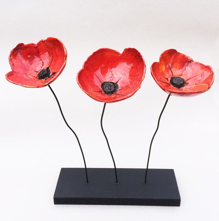 three red flowers are on a black stand