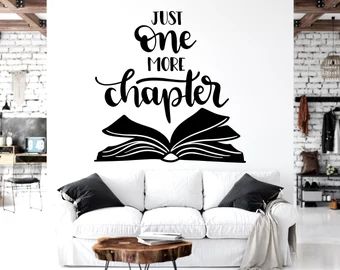 a living room with a white couch and black wall decal that says, just one more character