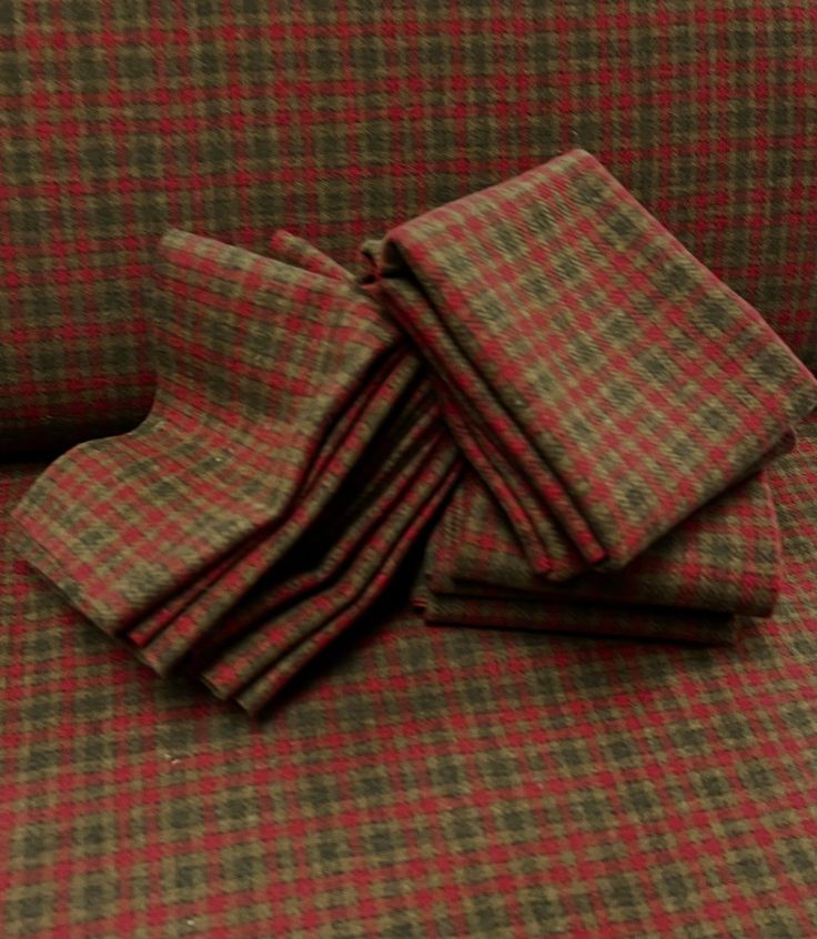 four pieces of cloth folded on the back of a couch with red and green checkered fabric