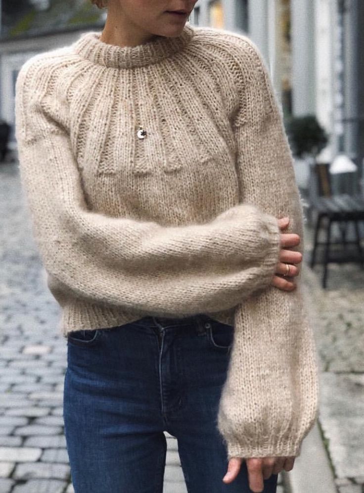 a woman standing on the street wearing a sweater