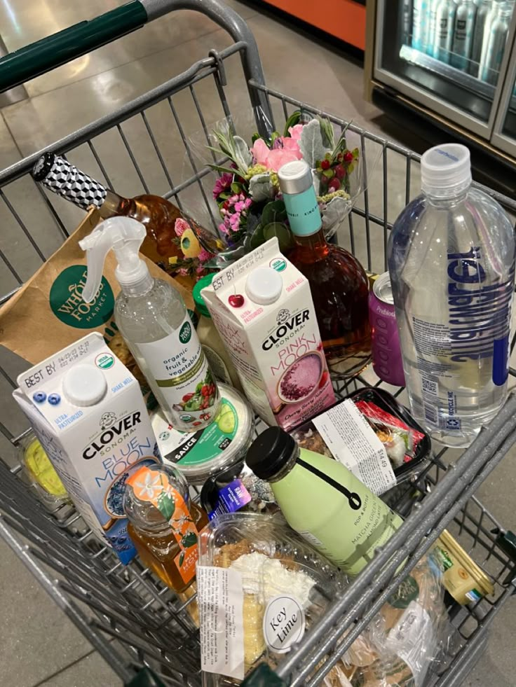 a shopping cart filled with lots of different types of food and drink items on the floor