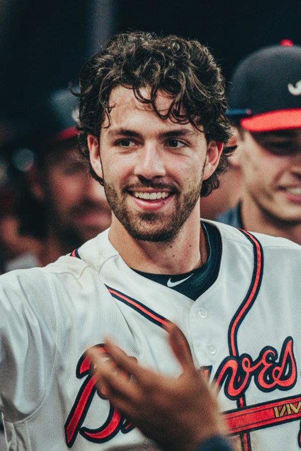 a baseball player is smiling and holding his hand out in the air with other players behind him