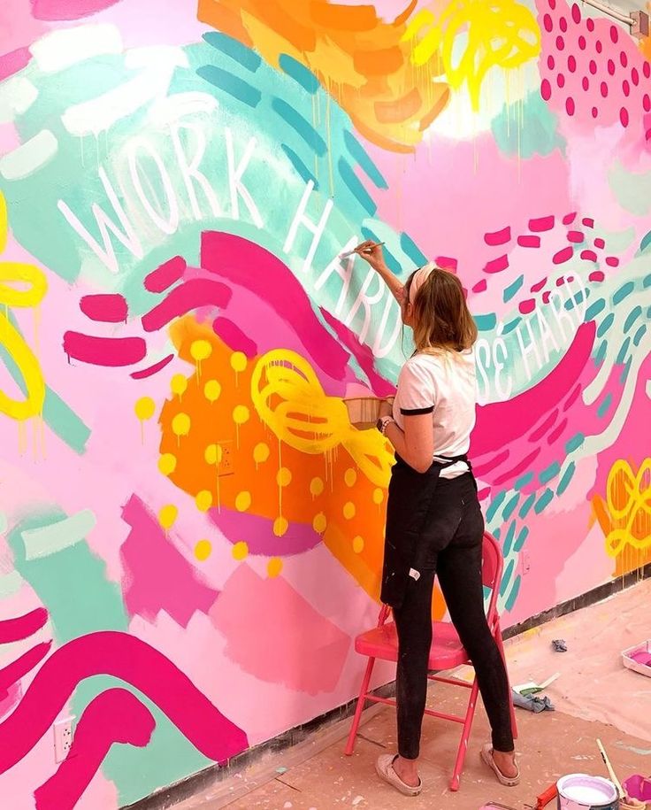 a woman is painting a large colorful wall