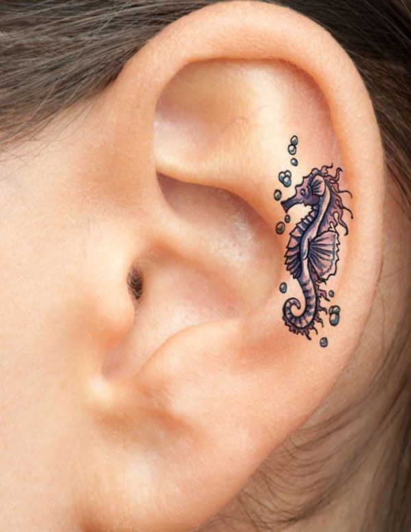 a close up of a person's ear with a dragon tattoo on the side