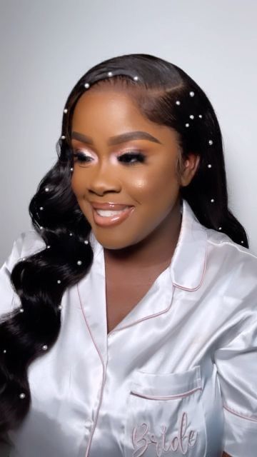 a woman with long black hair wearing a white robe and pearls on her head is smiling