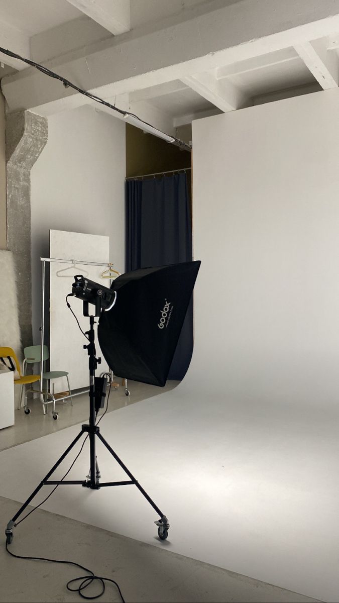 a photo studio with white walls and lighting equipment in front of the camera on a tripod