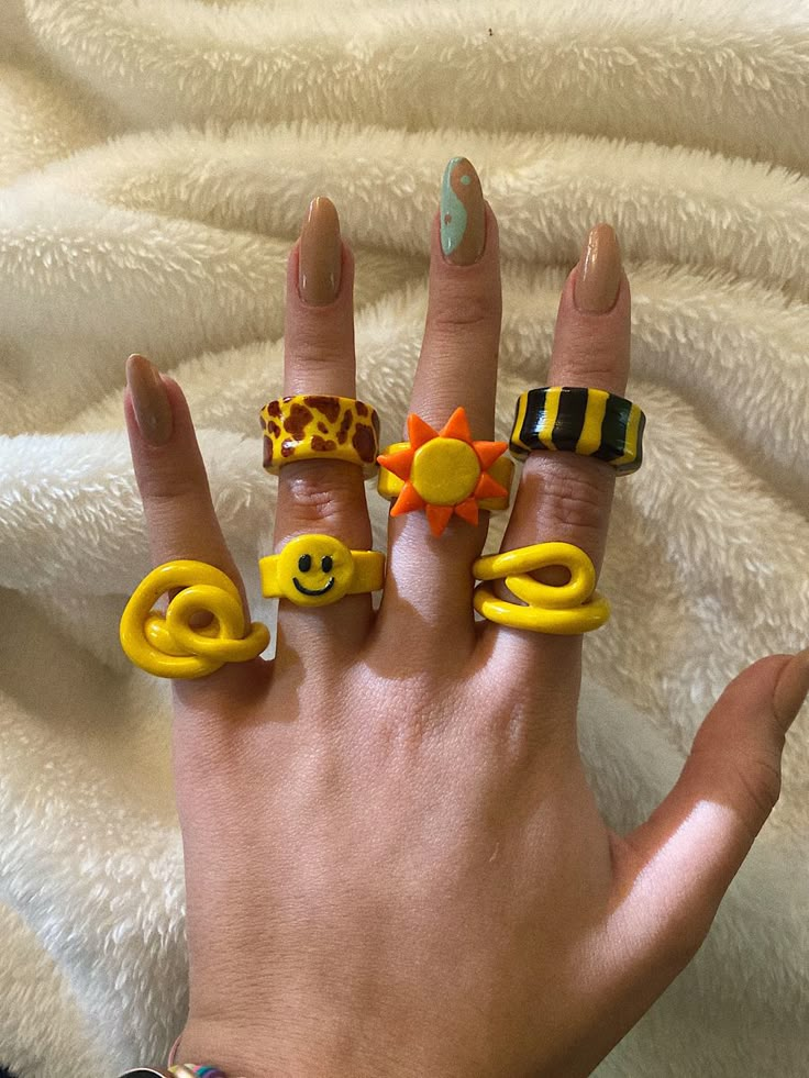 a woman's hand with five different rings on it and one has a smiley face