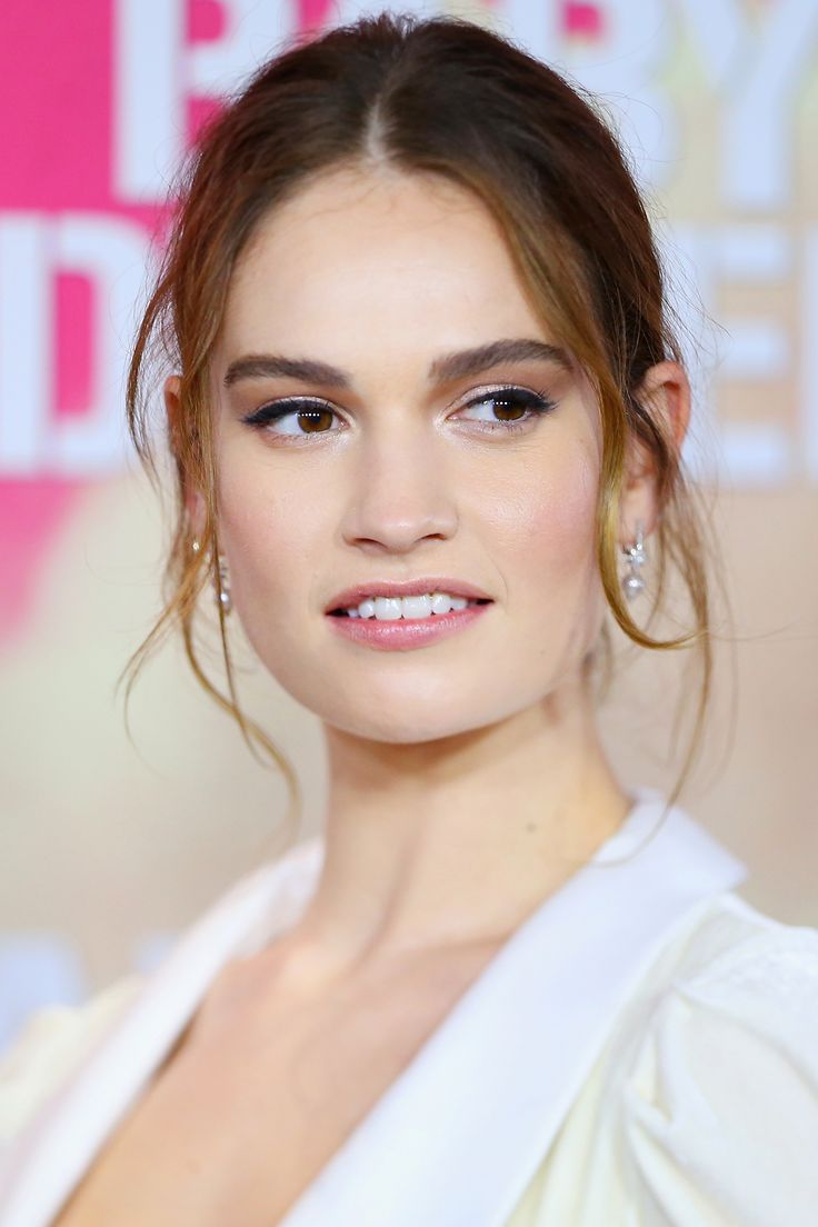 a woman with long hair and blue eyeshadow wearing a white dress at an event