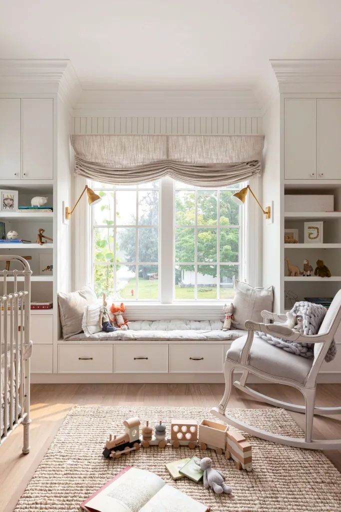 a baby's room with a rocking chair, window seat and bookshelf