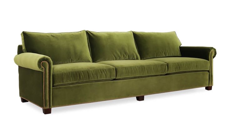 a green velvet couch with wooden legs