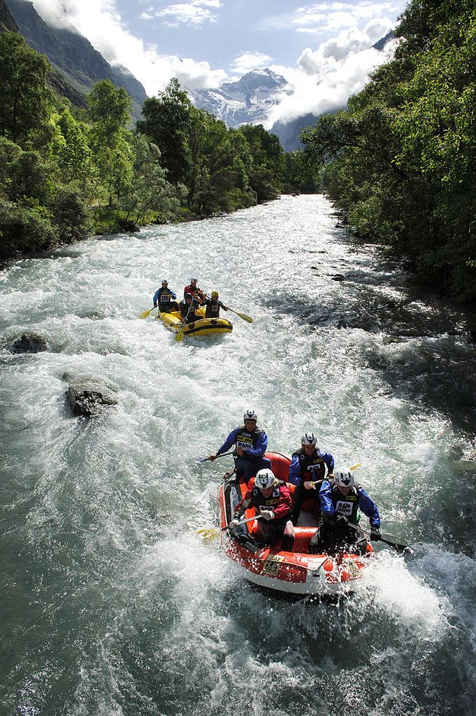 several people are rafting down a river with mountains in the background