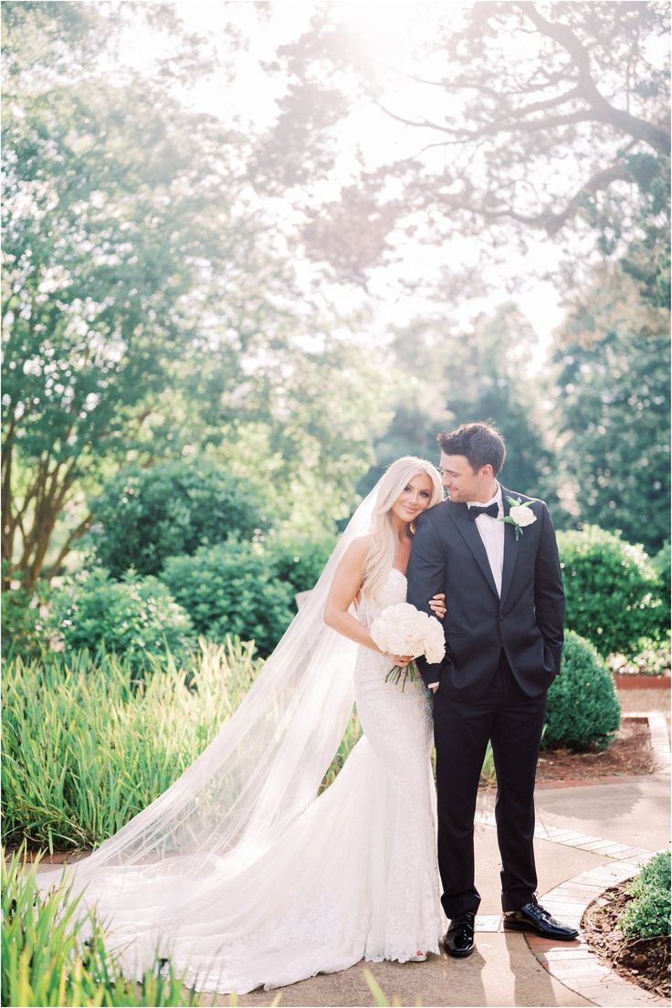 a bride and groom standing together in front of trees