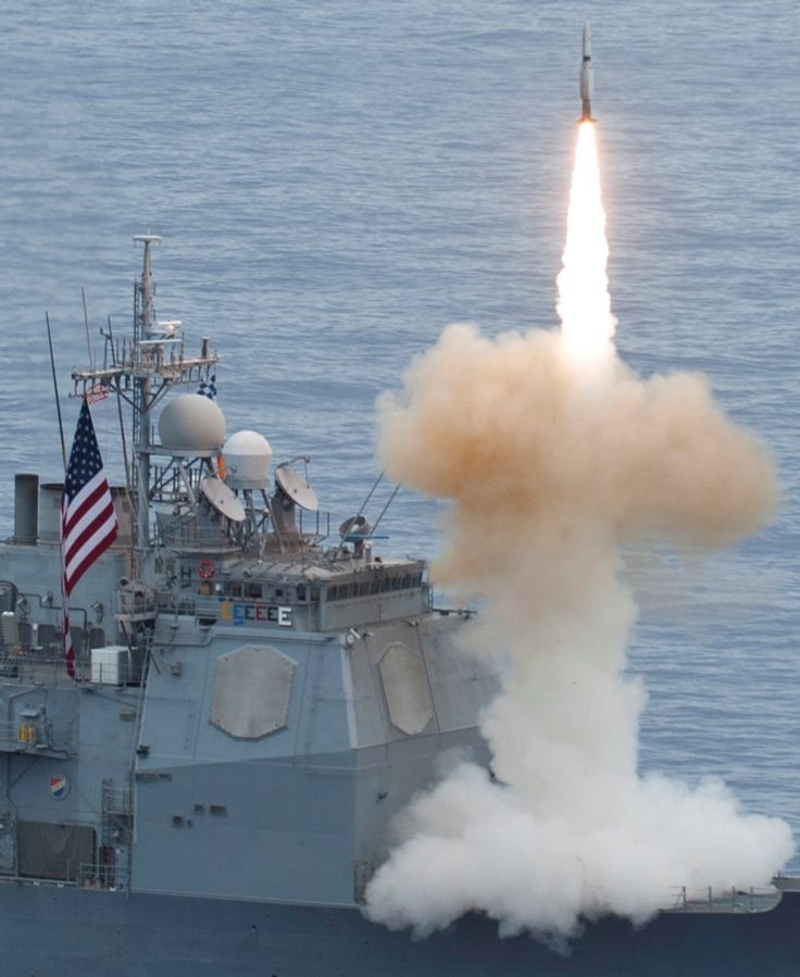 a navy ship with a missile launching from it's back end in the water