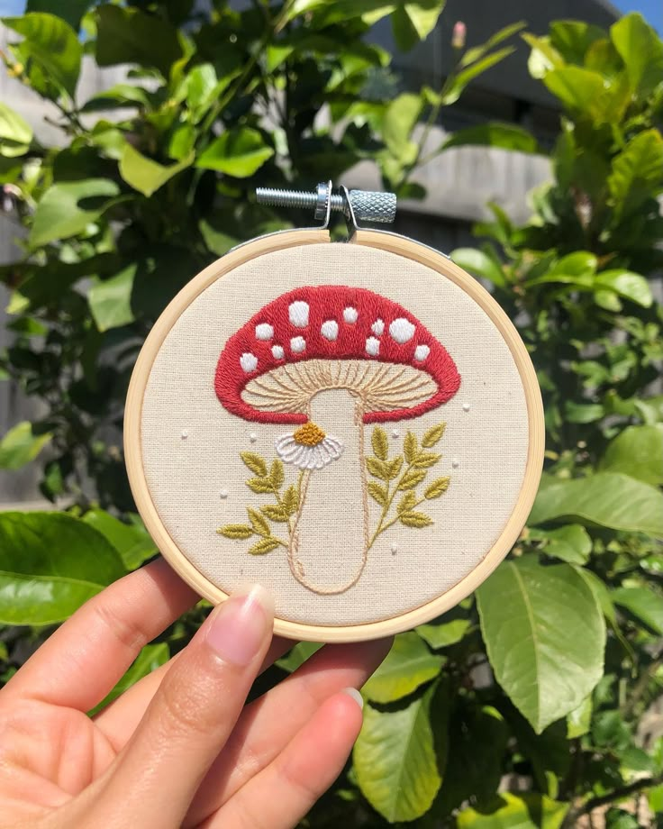 someone is holding up a small embroidered mushroom