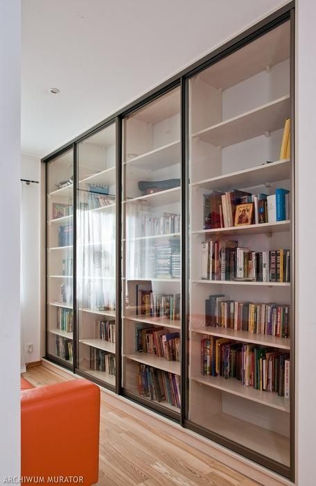 the bookshelves in this room are full of books and have glass doors on them