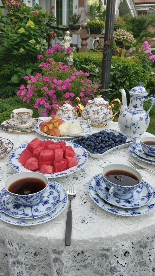 the table is set with tea, watermelon and blueberries for two people