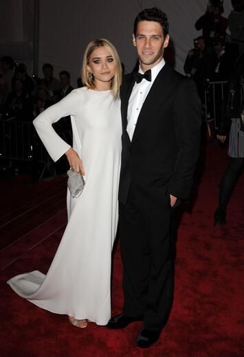 a man in a tuxedo standing next to a woman in a white dress