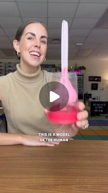 a woman sitting at a table with a pink object in her hand and the caption reads this is a model of the human