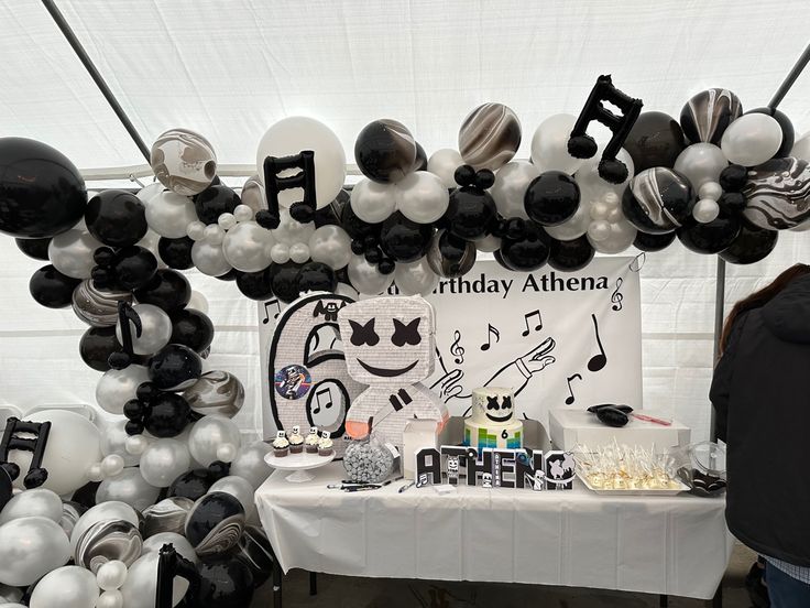 a table topped with balloons and musical notes on it's wall next to a sign that says happy birthday athena