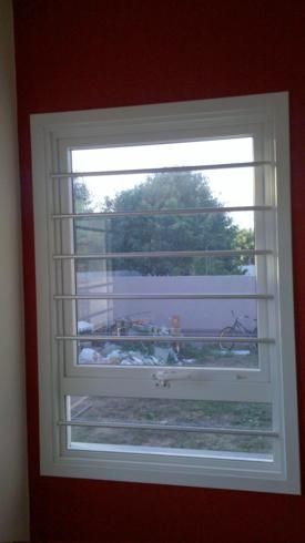 a window with blinds in the middle of it and a red painted wall behind it